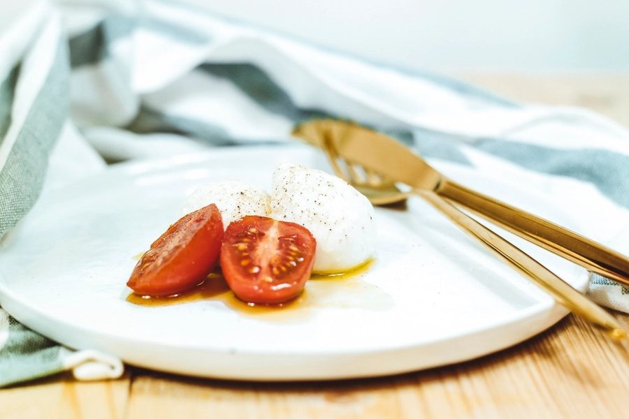 Une burrata et des tomates coupées sur une assiette blanche