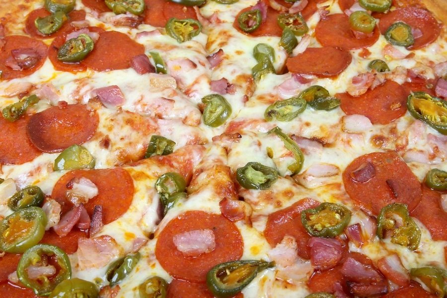 Une pizza couverte de salami et de rondelles de piment vert
