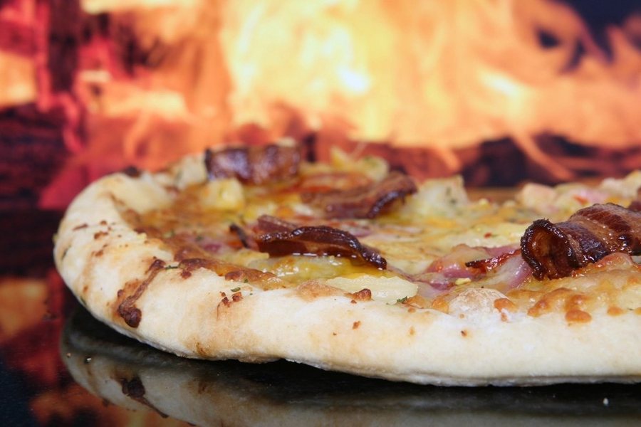 Une pizza qui cuit devant les flammes du four