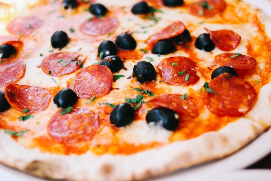 Une pizza au salami et aux olives noires, vue de près